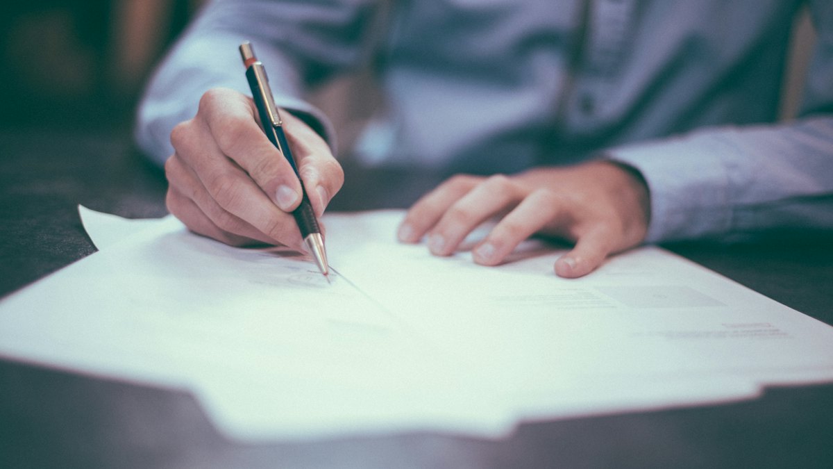 Mano firmando un documento con un bolígrafo