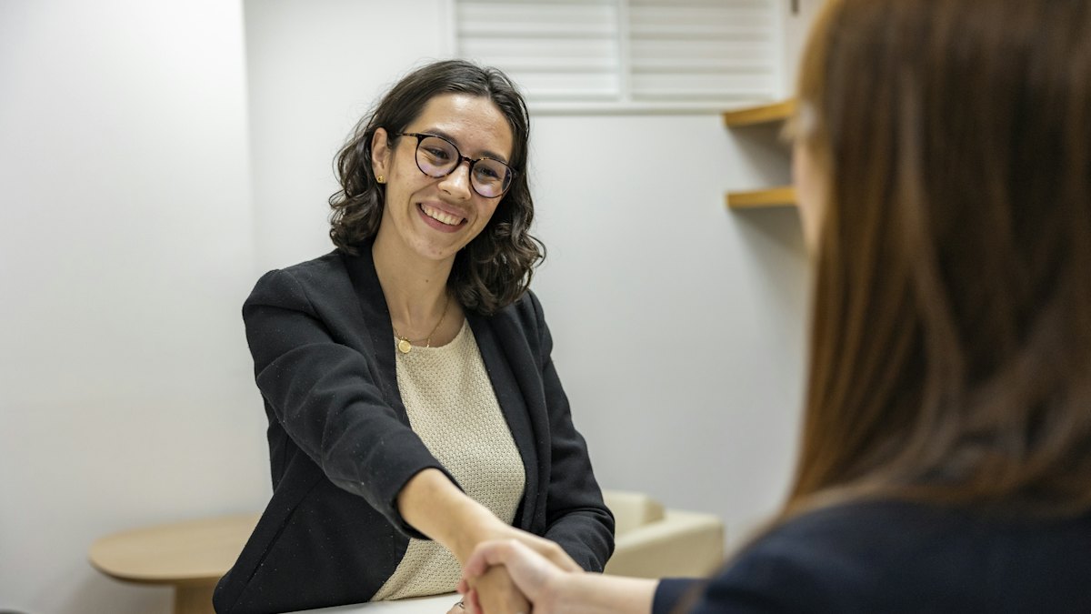 Dos personas dándose la mano en una entrevista de trabajo